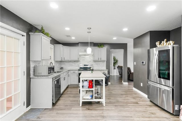 kitchen with tasteful backsplash, appliances with stainless steel finishes, light hardwood / wood-style floors, decorative light fixtures, and a center island