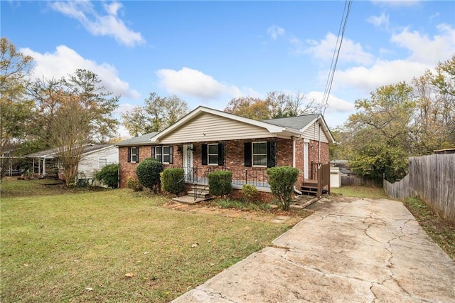 view of front of house featuring a porch, a front yard, brick siding, and fence