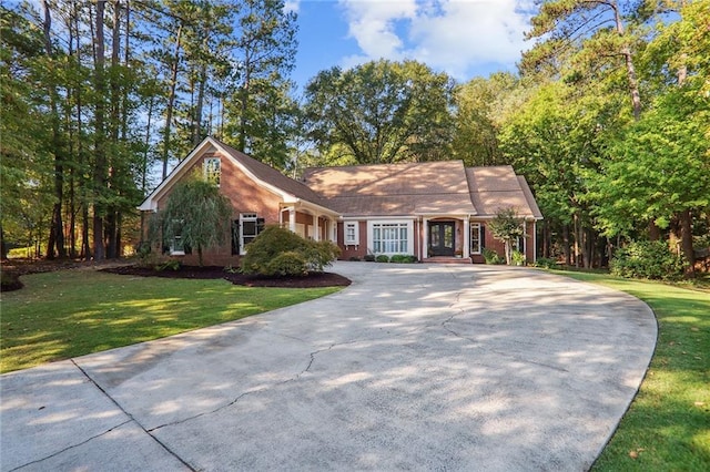 view of front facade with a front yard, concrete driveway, and brick siding