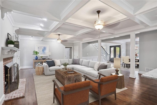 living area with a ceiling fan, a fireplace, beamed ceiling, and wood finished floors