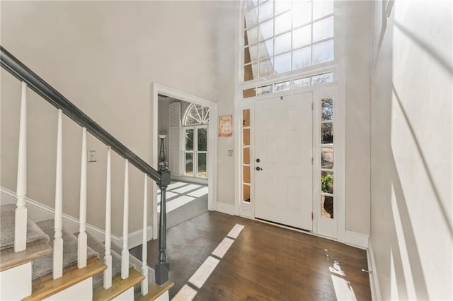 foyer featuring stairway, wood finished floors, baseboards, and a towering ceiling