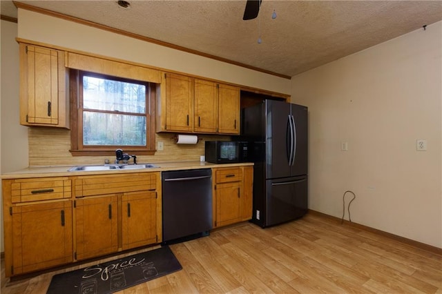 kitchen featuring sink, a textured ceiling, decorative backsplash, black appliances, and light wood-type flooring