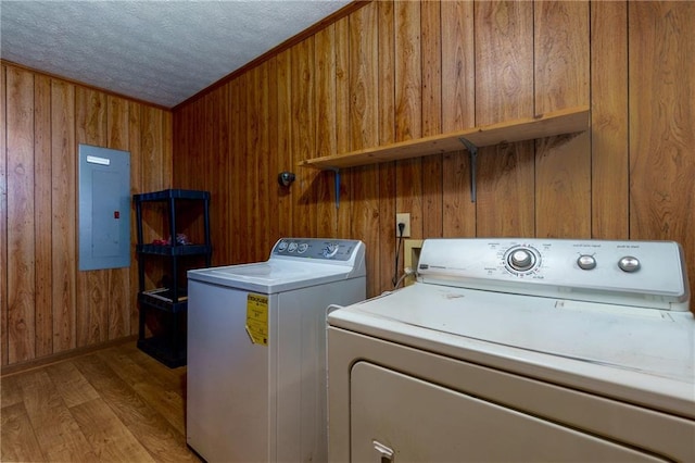 washroom featuring washer and dryer, wood walls, a textured ceiling, and electric panel