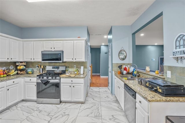 kitchen with a sink, marble finish floor, white cabinetry, and stainless steel appliances