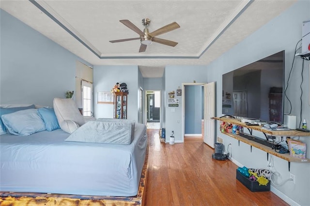 bedroom featuring baseboards, a tray ceiling, and wood finished floors