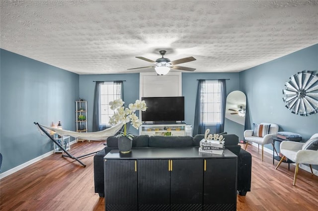 living area with plenty of natural light, wood finished floors, and a ceiling fan