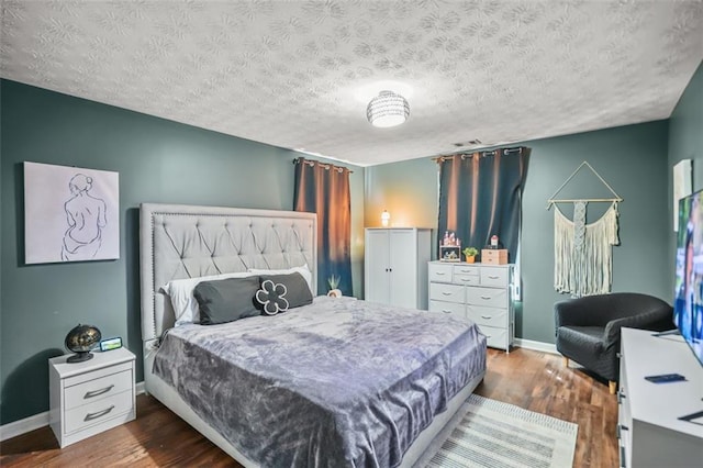 bedroom featuring wood finished floors, baseboards, and a textured ceiling