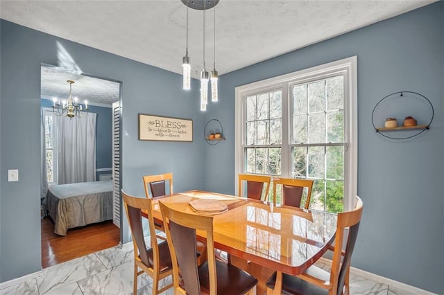 dining room featuring baseboards, a textured ceiling, marble finish floor, and a chandelier