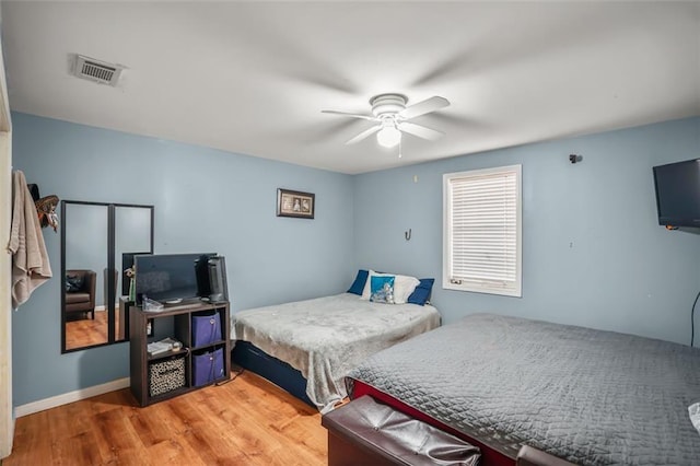 bedroom with ceiling fan, visible vents, baseboards, and wood finished floors