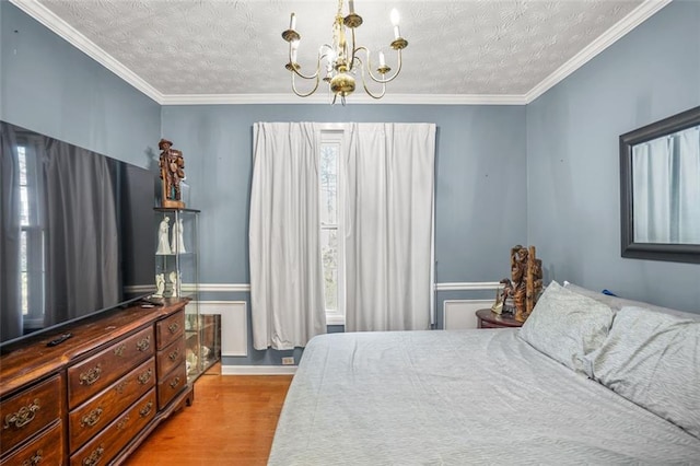 bedroom featuring a textured ceiling, an inviting chandelier, wood finished floors, and ornamental molding