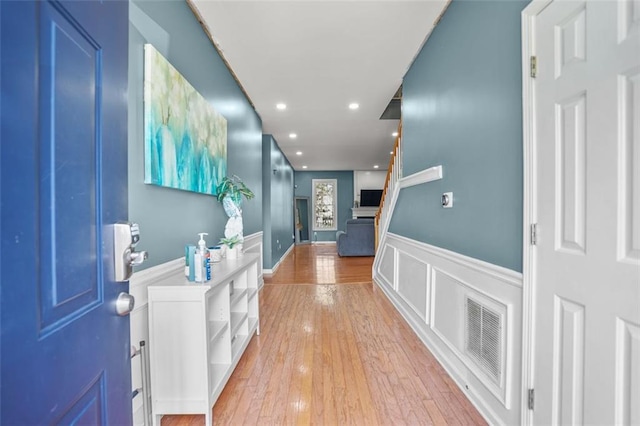 hallway featuring a wainscoted wall, visible vents, light wood-style flooring, recessed lighting, and a decorative wall