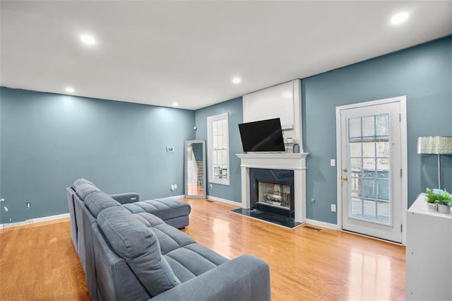 living area featuring wood finished floors, recessed lighting, a fireplace, and baseboards