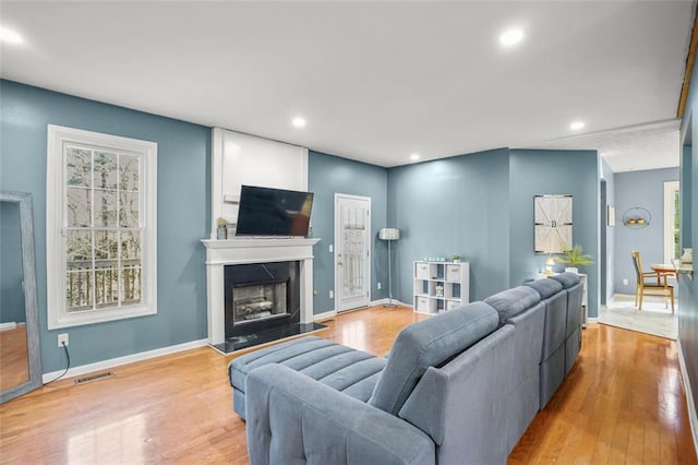 living room with visible vents, baseboards, wood finished floors, and a fireplace