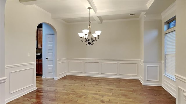 spare room with an inviting chandelier, hardwood / wood-style floors, crown molding, and beamed ceiling