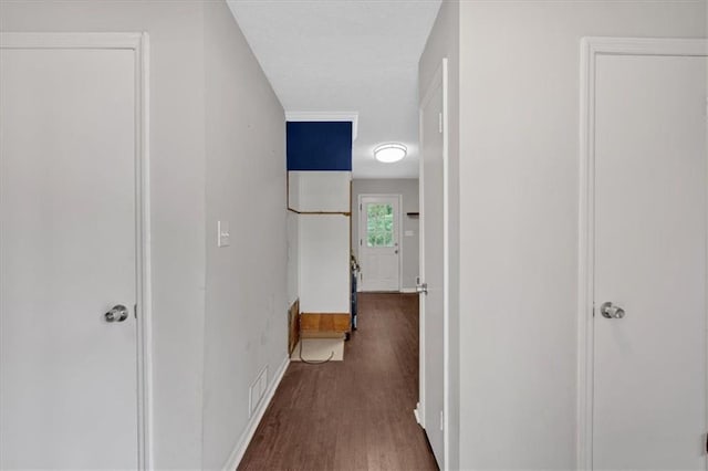 corridor with baseboards, visible vents, and wood finished floors