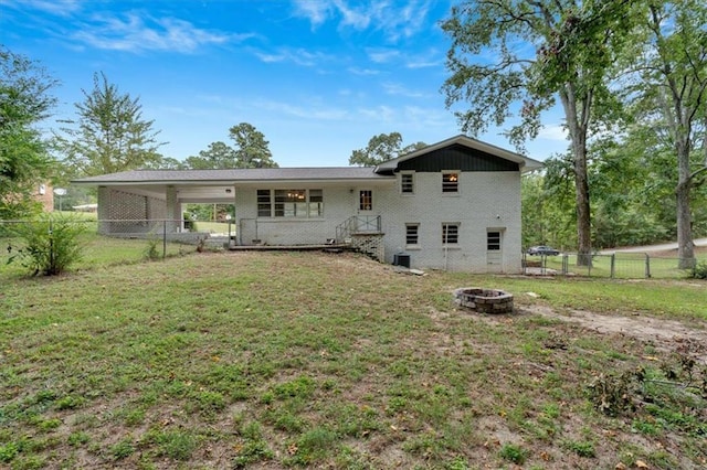 rear view of property featuring a fenced backyard, a carport, a yard, and a fire pit