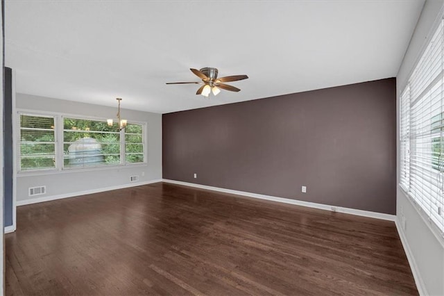 unfurnished room featuring visible vents, dark wood finished floors, ceiling fan with notable chandelier, and baseboards