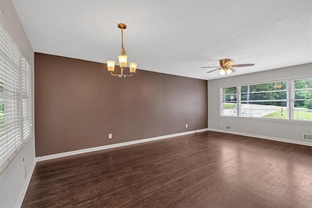 empty room with baseboards, visible vents, ceiling fan with notable chandelier, and dark wood-type flooring