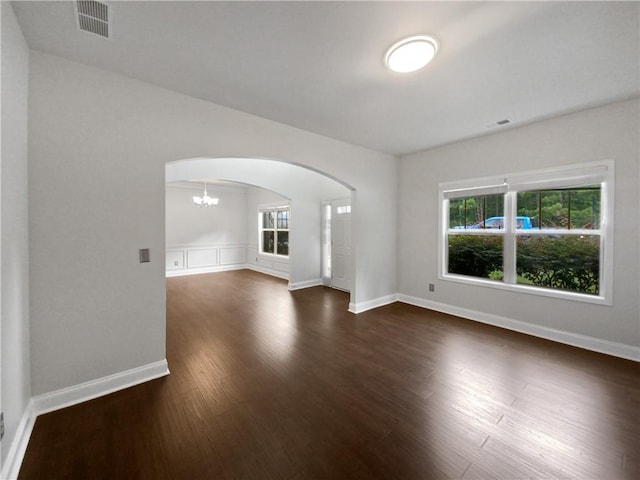 unfurnished living room featuring a notable chandelier and dark wood-type flooring