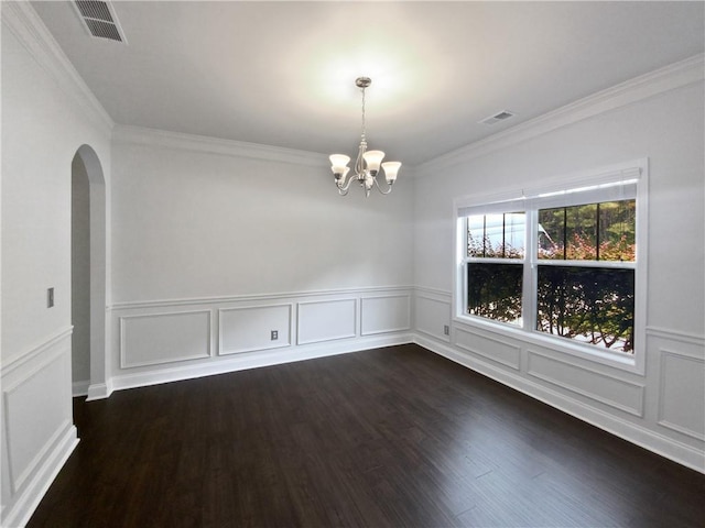 spare room featuring dark hardwood / wood-style floors, ornamental molding, and a chandelier