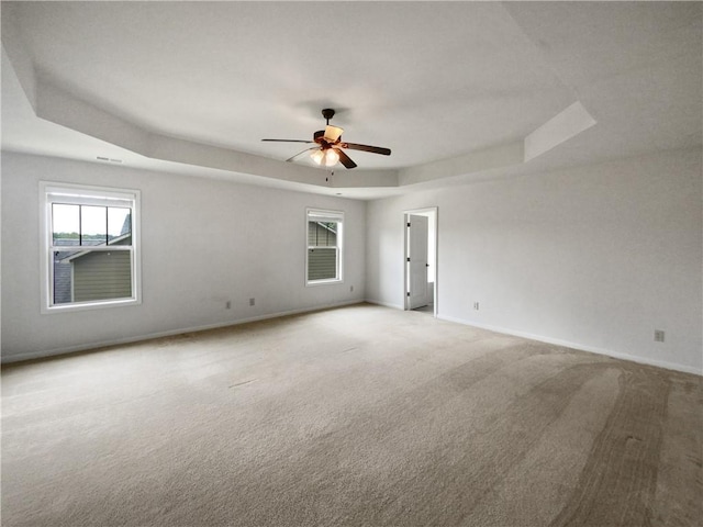 carpeted spare room featuring ceiling fan and a tray ceiling