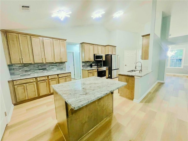 7675 Lanier View Rdg, Cumming, GA 30041 - kitchen featuring appliances with stainless steel finishes, light wood-style flooring, a peninsula, decorative backsplash, and high vaulted ceiling