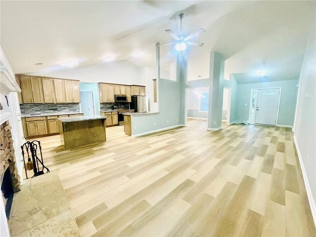7675 Lanier View Rdg, Cumming, GA 30041 - kitchen featuring open floor plan, stainless steel appliances, vaulted ceiling, a stone fireplace, and ceiling fan