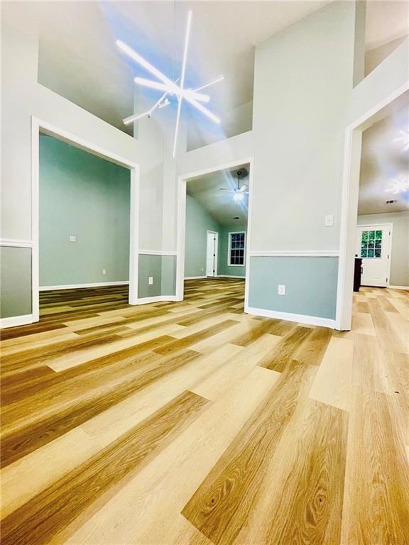 7675 Lanier View Rdg, Cumming, GA 30041 - unfurnished living room featuring high vaulted ceiling, wood finished floors, baseboards, and a chandelier