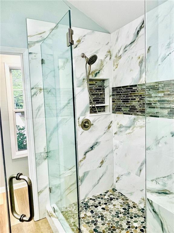 7675 Lanier View Rdg, Cumming, GA 30041 - full bath with a marble finish shower, vaulted ceiling, and wood finished floors