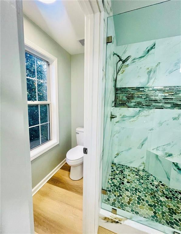 7675 Lanier View Rdg, Cumming, GA 30041 - bathroom with a marble finish shower, wood finished floors, toilet, and baseboards