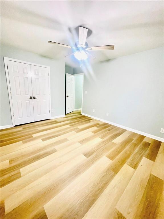 7675 Lanier View Rdg, Cumming, GA 30041 - unfurnished bedroom with light wood-type flooring, baseboards, ceiling fan, and a closet