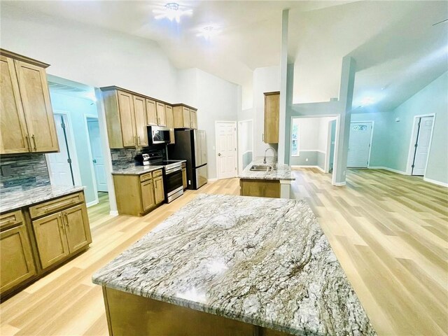7675 Lanier View Rdg, Cumming, GA 30041 - kitchen with appliances with stainless steel finishes, tasteful backsplash, light stone counters, light wood-style flooring, and high vaulted ceiling