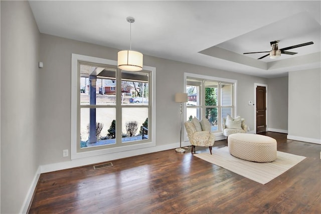 living area featuring wood finished floors, a raised ceiling, visible vents, and baseboards