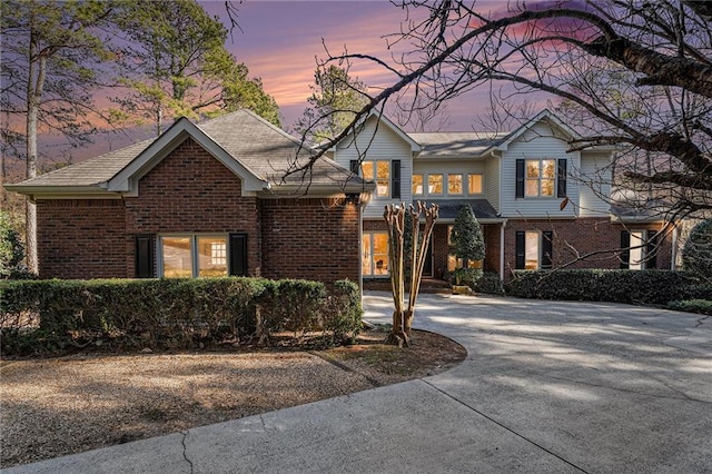 traditional-style house featuring driveway and brick siding