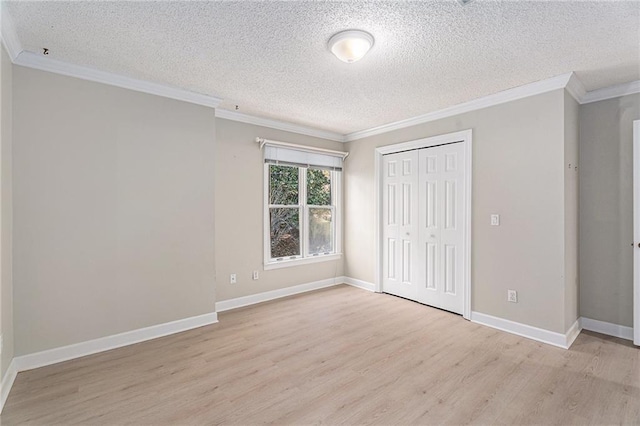 unfurnished bedroom with baseboards, ornamental molding, a textured ceiling, light wood-type flooring, and a closet