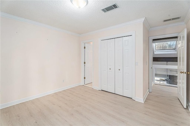 unfurnished bedroom with ornamental molding, visible vents, light wood-style flooring, and a textured ceiling