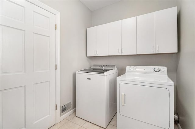 laundry room with light tile patterned floors, separate washer and dryer, visible vents, baseboards, and cabinet space