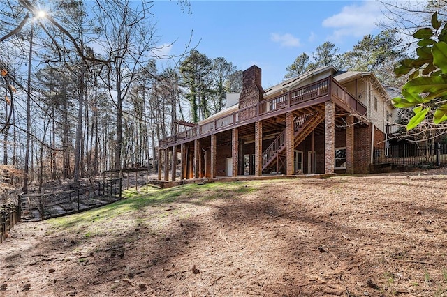 rear view of house with a chimney, stairway, fence, a wooden deck, and brick siding