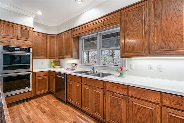 kitchen with ornamental molding, brown cabinets, stainless steel appliances, light countertops, and a sink