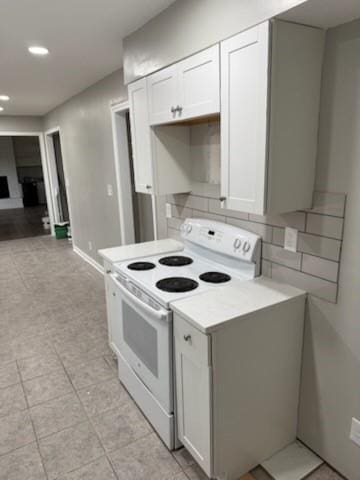 kitchen featuring white electric stove, decorative backsplash, open floor plan, light countertops, and white cabinetry