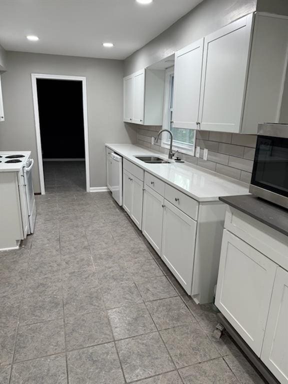 kitchen with backsplash, white cabinetry, stainless steel appliances, and a sink