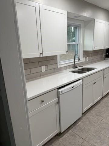 kitchen with dishwasher, light countertops, a sink, and decorative backsplash