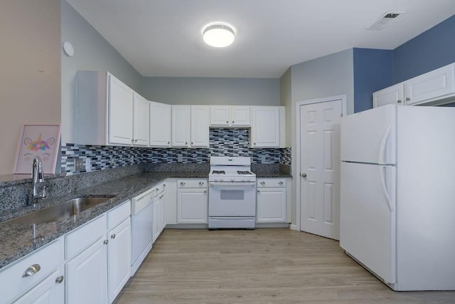 kitchen featuring sink, white cabinetry, dark stone countertops, white appliances, and backsplash