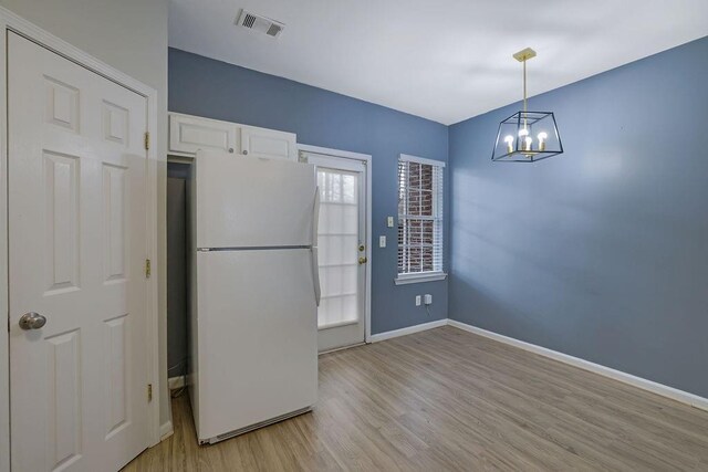 kitchen with decorative light fixtures, white cabinetry, white fridge, a notable chandelier, and light hardwood / wood-style flooring