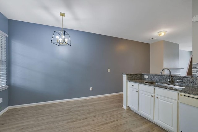 kitchen with pendant lighting, sink, dishwasher, dark stone countertops, and white cabinets