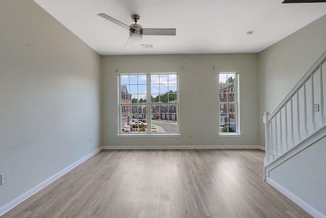 empty room with ceiling fan and light hardwood / wood-style flooring