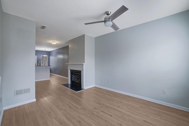 unfurnished living room featuring light hardwood / wood-style floors and ceiling fan with notable chandelier