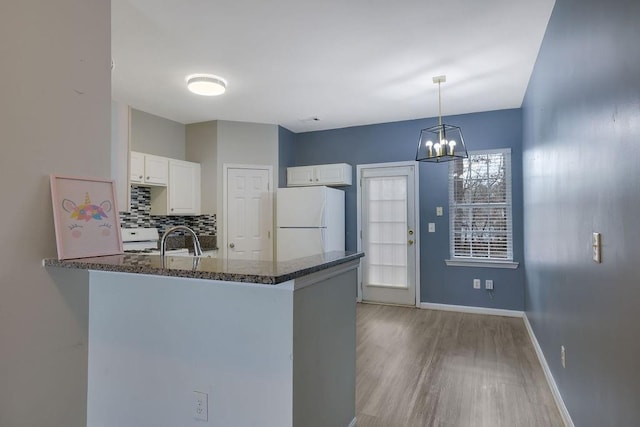 kitchen with decorative light fixtures, white cabinetry, decorative backsplash, white refrigerator, and kitchen peninsula