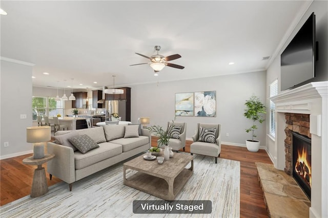 living room with ornamental molding, light hardwood / wood-style flooring, a fireplace, and ceiling fan