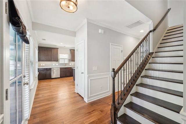 stairway with crown molding and hardwood / wood-style flooring